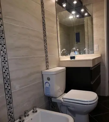 a bathroom with a toilet and a sink and a mirror at Torre del Lago I in Villa Carlos Paz
