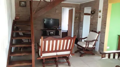 a living room with a staircase and a chair and a television at Bosysol en las sierras in Merlo