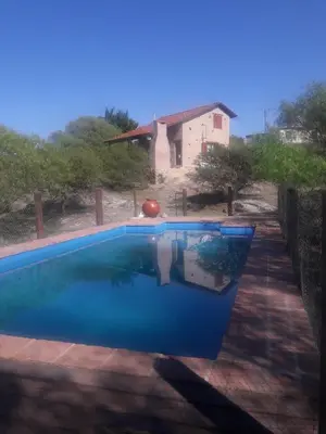 a swimming pool in front of a house at Cabañas las Vertientes in Villa Parque Siquiman
