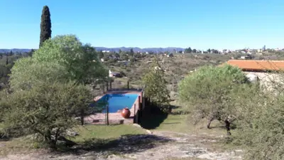 a house with a swimming pool in a field with trees at Cabañas las Vertientes in Villa Parque Siquiman