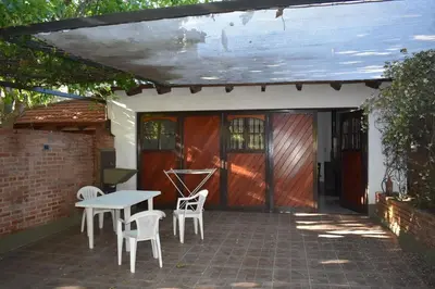 a patio with a table and chairs and a wooden door at Dos ruedas in Mina Clavero
