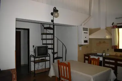 a living room with a kitchen and a spiral staircase at Dos ruedas in Mina Clavero