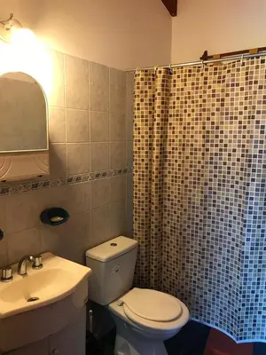 a bathroom with a toilet and a sink and a mirror at Cabañas Luz de Luna in Santa Rosa de Calamuchita