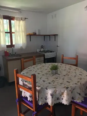 a kitchen with a table and chairs and a kitchen with a table and a table at Cabañas Luz de Luna in Santa Rosa de Calamuchita
