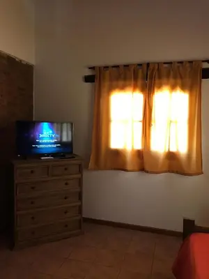 a television sitting on a dresser in front of a window at Cabañas Luz de Luna in Santa Rosa de Calamuchita