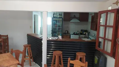 a kitchen with a counter and some wooden stools at Complejo LUMA, Con Pileta in Villa Dolores