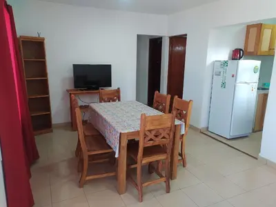 a kitchen with a table and chairs and a refrigerator at Complejo LUMA, Con Pileta in Villa Dolores