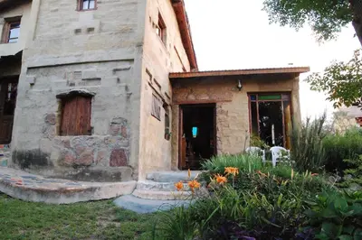 an old stone building with a door and some flowers at Casa Amarilla in Mina Clavero