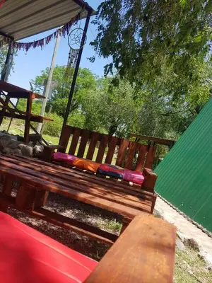 a wooden bench with pillows next to a clock tower at Cabañas Pancho Segunda Usina in Embalse