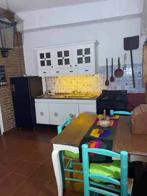 a kitchen with white cabinets and a table with chairs at Cerro Chico Brochero in Villa Cura Brochero