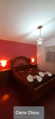 a red bedroom with a bed with two towels on it at Cerro Chico Brochero in Villa Cura Brochero