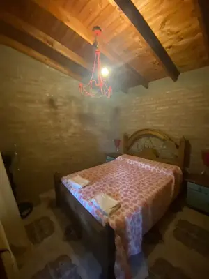 a room with a bed in a attic with a chandelier at Cerro Chico Brochero in Villa Cura Brochero