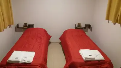 two beds with red covers in a room at Posada Entre Dos in Mina Clavero