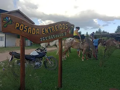 a sign for a postada entrance dog with people on horses at Posada Entre Dos in Mina Clavero