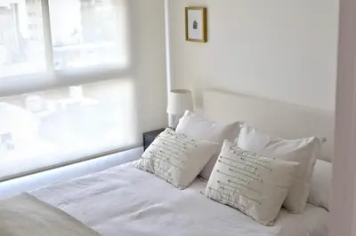 a white bed with white pillows and a window at 370 General Simón Bolívar in Cordoba