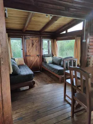 a room with two beds and a chair in a cabin at Cabaña de Troncos en la montaña in Mina Clavero