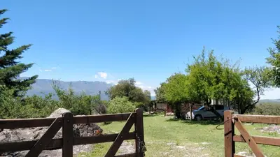 a fence in front of a yard with a house at Cabaña de Troncos en la montaña in Mina Clavero