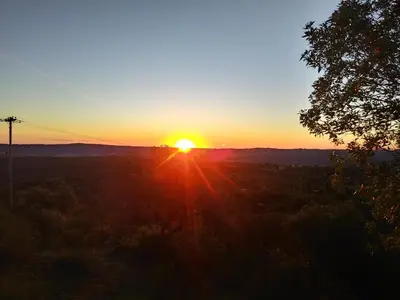 a sunset with the sun setting in the sky at Cabaña de Troncos en la montaña in Mina Clavero