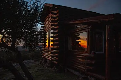 a log cabin with a window at night at Cabaña de Troncos en la montaña in Mina Clavero