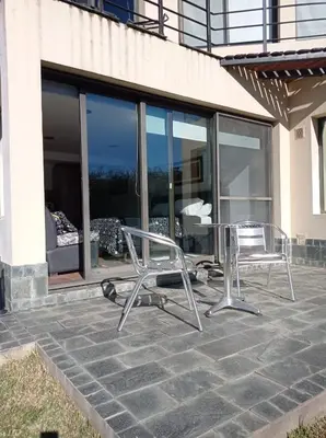 a patio with two chairs and a table in front of a building at La Macarena Suites in Villa General Belgrano