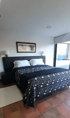 a bedroom with a bed with a black and white blanket at La Macarena Suites in Villa General Belgrano
