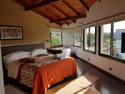 a bedroom with a bed and large windows at La Macarena Suites in Villa General Belgrano