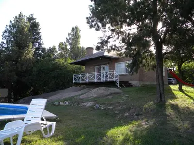 a house with a pool and two chairs in front of it at Casa en Playa Perelli in Villa Carlos Paz