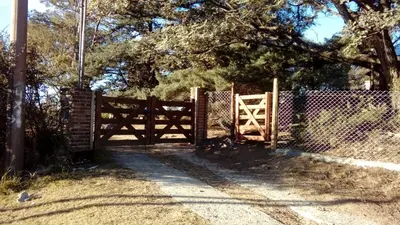 a wooden gate with a fence in front of a tree at Casa en Playa Perelli in Villa Carlos Paz