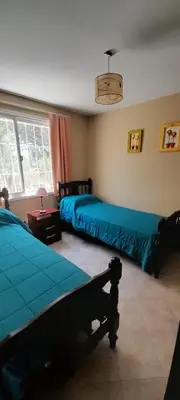 a bedroom with two beds and a table and windows at Casa en Playa Perelli in Villa Carlos Paz