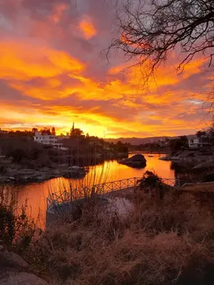 a sunset over a body of water with a bridge at Casa en Playa Perelli in Villa Carlos Paz