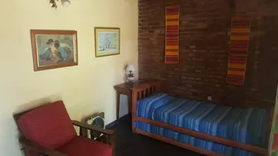 a bedroom with a bed and a chair in a room at Casa en Playa Perelli in Villa Carlos Paz