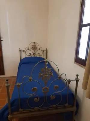 a bed in a room with a blue blanket on it at Hostal Antigua Casa Criolla in Los Reartes