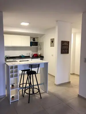 a kitchen with two bar stools and a counter top at Dpto Teatro Melos microcentro pileta y cochera in Villa Carlos Paz