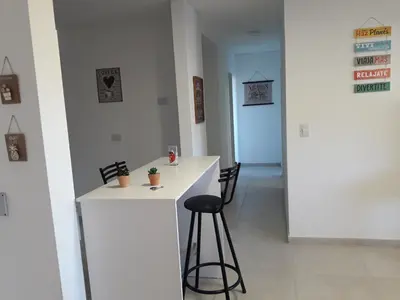 a white bar with a stool in a room at Dpto Teatro Melos microcentro pileta y cochera in Villa Carlos Paz