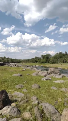a grassy field with rocks and a river at cabañas Tierra Kamiare 1 in Amboy