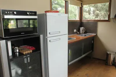 a small kitchen with a refrigerator and a microwave at cabañas Tierra Kamiare 1 in Amboy