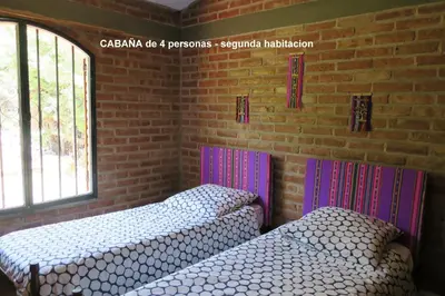 two beds in a room with a brick wall at Cabañas A la Maison in Mina Clavero