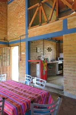 a kitchen with a table with chairs and a refrigerator at Cabañas A la Maison in Mina Clavero