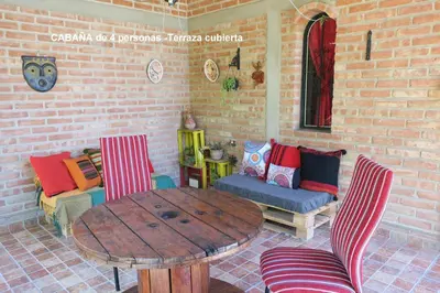a patio with a table and chairs and a couch at Cabañas A la Maison in Mina Clavero