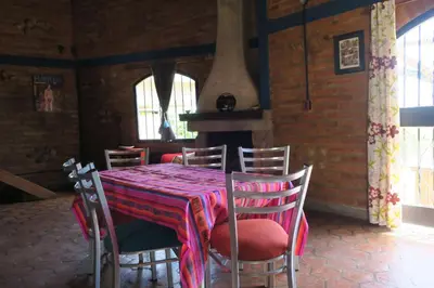 a dining room with a table and chairs and windows at Cabañas A la Maison in Mina Clavero