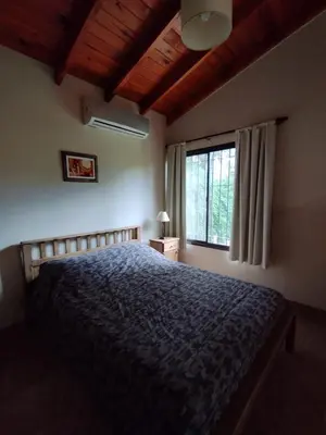 a bedroom with a bed with a blue comforter and a window at Aldea del Río in Santa Rosa de Calamuchita