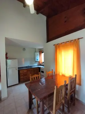 a kitchen with a wooden table and a table and chairs at Aldea del Río in Santa Rosa de Calamuchita