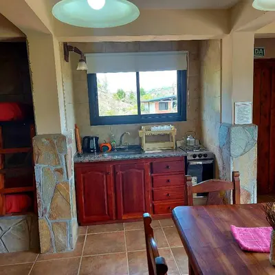 a kitchen with a table and a sink and a window at La Ponderosa Cumbrecita in La Cumbrecita