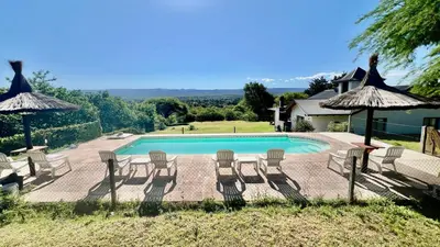 a swimming pool with lawn chairs and umbrellas at Fincas del Faldeo in Villa General Belgrano