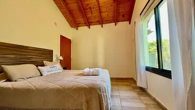 a bedroom with a bed and a large window at Fincas del Faldeo in Villa General Belgrano