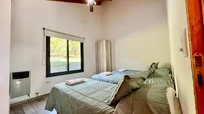 two beds in a room with a window at Fincas del Faldeo in Villa General Belgrano