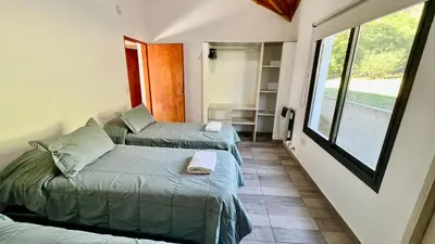 two beds in a small room with a window at Fincas del Faldeo in Villa General Belgrano