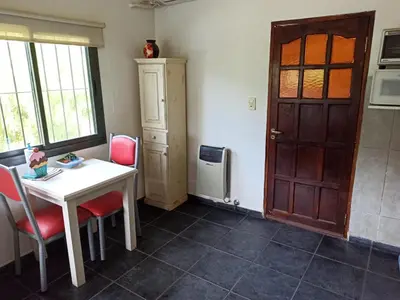 a room with a table and chairs and a door at Cabañas Noscohue in Villa General Belgrano