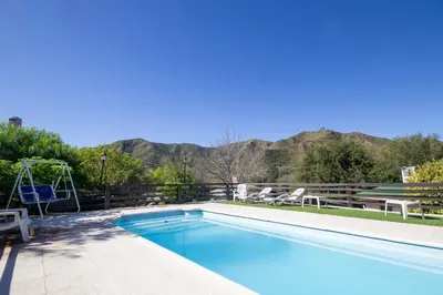 a swimming pool with mountains in the background at Cabañas Noscohue in Villa General Belgrano