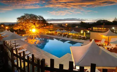 a large pool with umbrellas and tables and chairs at Cabañas Loma Azul in Villa General Belgrano